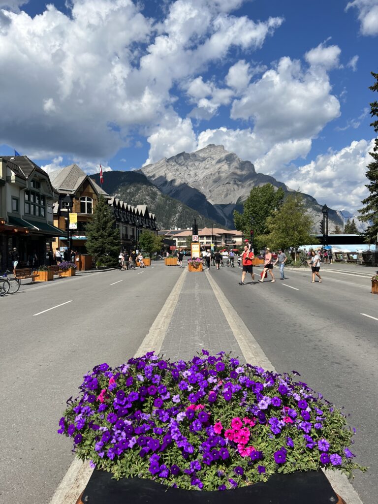 Banff Avenue with flower planters and Cascade Mountain in the background.