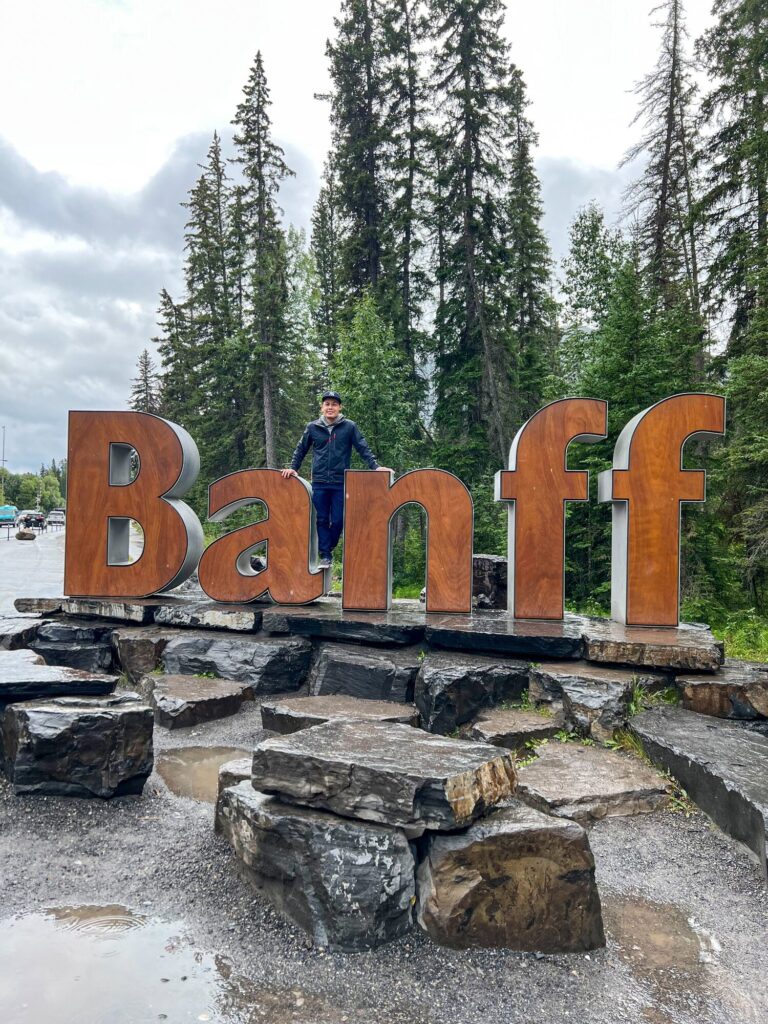 Traveler standing beside the large Banff town sign in Alberta, Canada.